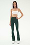 A woman wears the SPLITS59 Raquel High Waist Flared Legging in Military/White, paired with a white crop top and white sneakers, standing against a plain white background.