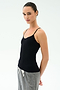 A person wears the SPLITS59 Loren Seamless Waist Length Tank in black and gray drawstring pants, standing slightly sideways against a white background.