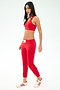A woman channels relaxed Los Angeles style in a red sports bra and SPLITS59 Sonja Fleece Sweatpant in Pirate Red with a white drawstring, paired with white sneakers with red stripes against a plain white background.