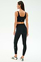 Woman faces away in SPLITS59 Airweight Rib High Waist 7/8 leggings (Black) and a black sports bra, paired with white sneakers featuring green stripes—perfect for hot yoga or Pilates—set against a plain light background.