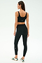Woman faces away in SPLITS59 Airweight Rib High Waist 7/8 leggings (Black) and a black sports bra, paired with white sneakers featuring green stripes—perfect for hot yoga or Pilates—set against a plain light background.
