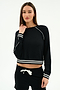 A woman wears the SPLITS59 Brooks Fleece Sweatshirt With Stripe in black/white, featuring long sleeves and striped cuffs/hem, paired with black drawstring shorts against a plain white background.