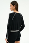 A person wearing the SPLITS59 Brooks Fleece Sweatshirt With Stripe in black/white, paired with matching black shorts, is seen from behind against a plain background.