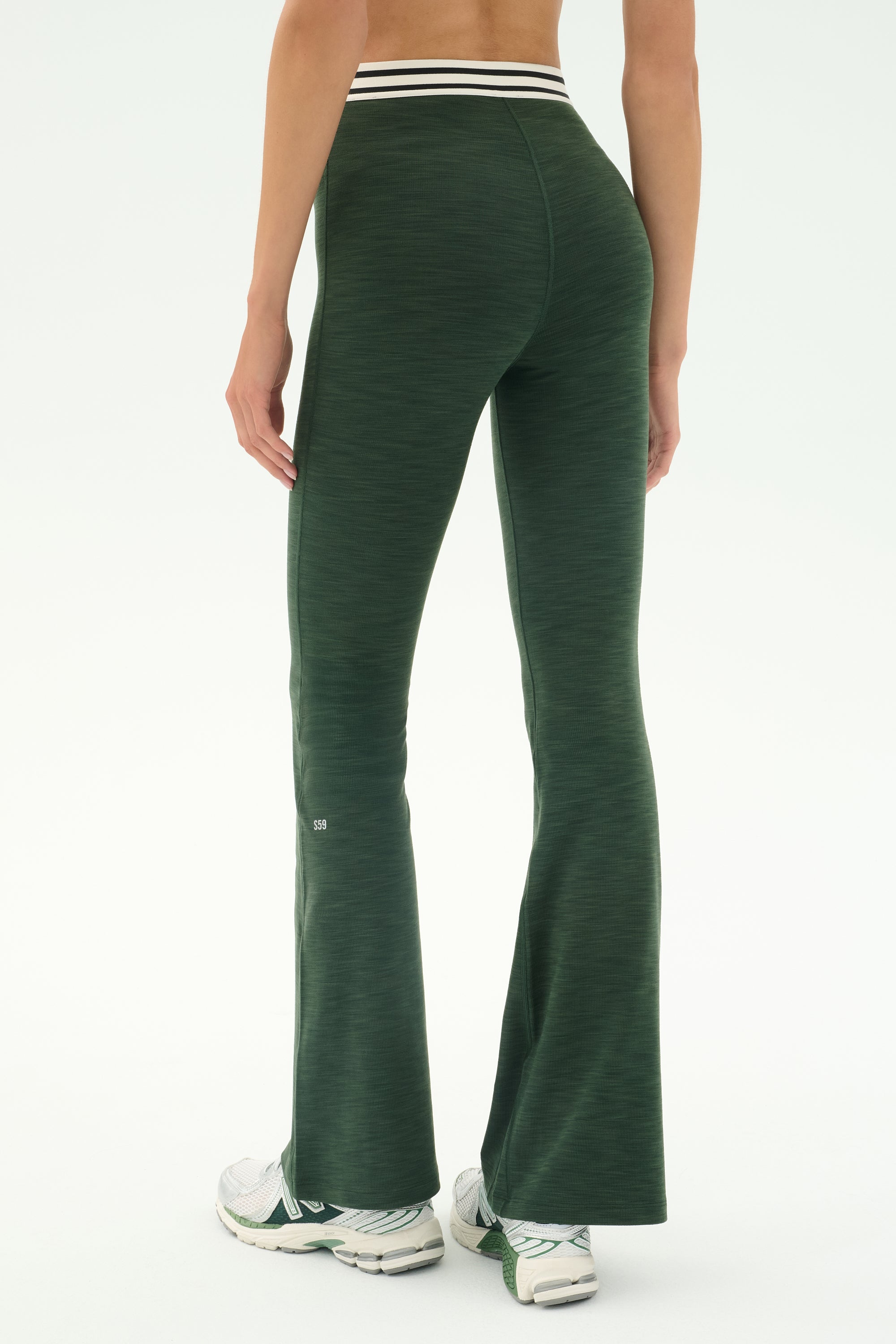 Person wearing SPLITS59 Raquel Active Rib Flare - Heather Military leggings with a white-striped waistband and white athletic shoes, standing on a light background.