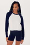 A woman in a Indigo/White Warm Up Crop Fleece Sweatshirt by SPLITS59, paired with black spandex shorts, standing against a white background.