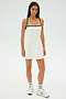 A person is wearing the Monah Rigor Dress in White/Arugula by SPLITS59, paired with sneakers, standing on a light background.