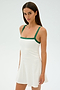 The woman is elegantly dressed in SPLITS59's Monah Rigor Dress in White/Arugula, featuring green spandex straps, against a plain background.
