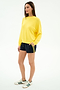 A person stands against a white background wearing an Andie Oversized Fleece Sweatshirt in bright yellow by SPLITS59, navy shorts with yellow stripes, and white sneakers with green stripes.