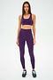 A person wearing the SPLITS59 Ella Airweight Bra in Black Currant/Indigo and leggings with a black stripe stands on a plain background, ready for hot yoga in sleek black sneakers.