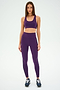 A person wearing the SPLITS59 Ella Airweight Bra in Black Currant/Indigo and leggings with a black stripe stands on a plain background, ready for hot yoga in sleek black sneakers.