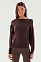 A woman with long straight hair stands facing the camera, wearing a plain dark long-sleeve top and matching leggings against a neutral background, showcasing the Sonja Fleece Sweatshirt in Dark Chocolate by SPLITS59.