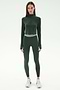 A woman faces forward wearing SPLITS59’s Bailey Active Rib High Waist 7/8 leggings in Heather Military with a matching dark green zip-up athletic top and white sneakers, set against a white background.