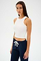 Someone in a SPLITS59 Kiki Rib Crop Tank - White and dark drawstring pants stands against a plain background.