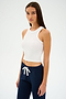 Someone in a SPLITS59 Kiki Rib Crop Tank - White and dark drawstring pants stands against a plain background.