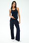 A woman stands against a plain background wearing the SPLITS59 Mel Airweight Lite Tank in Indigo, matching wide-leg pants with a white stripe, and white sneakers.