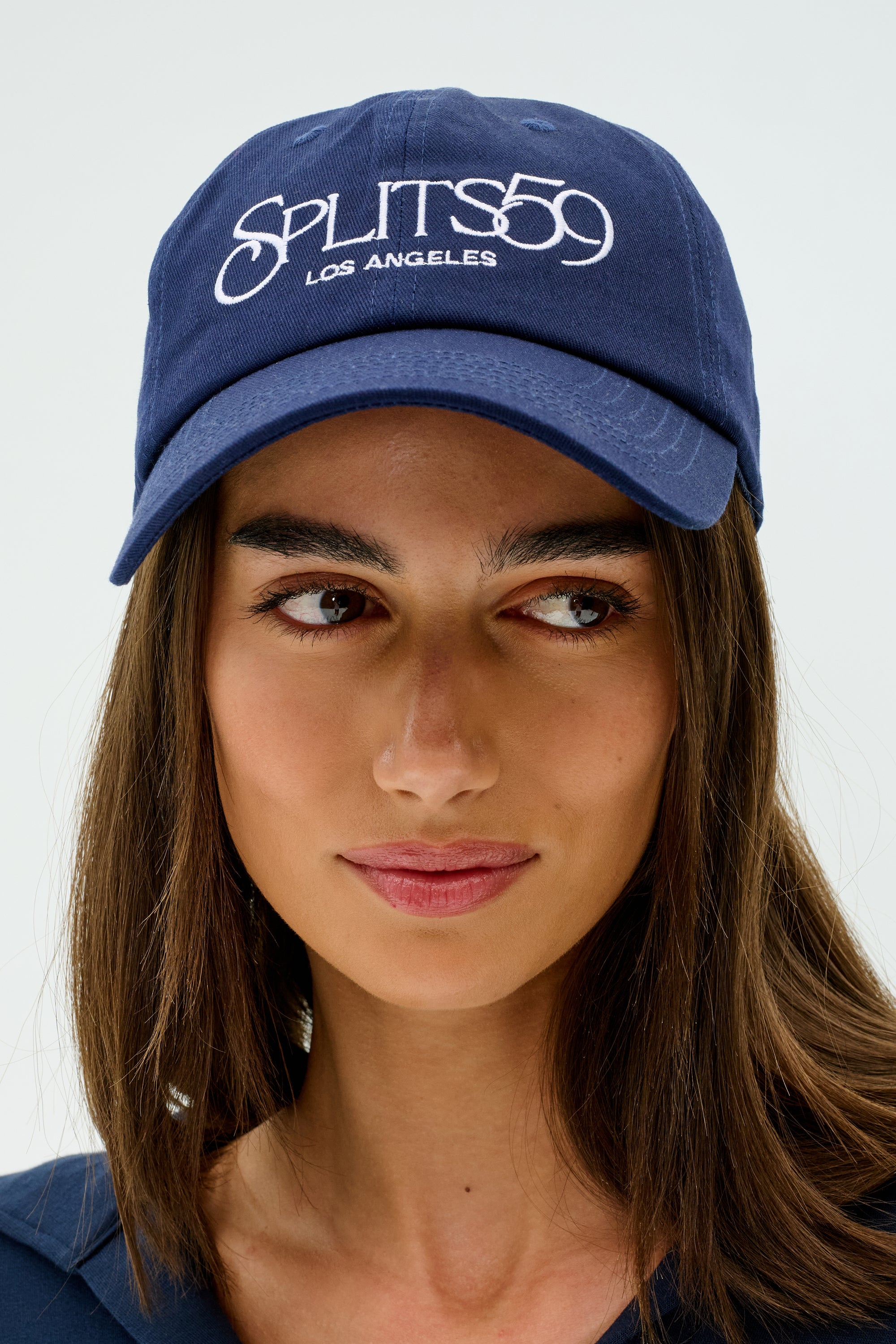 A person wearing a Tennis Cap - Indigo from SPLITS59, featuring "Splits59 Los Angeles" embroidered on the front.