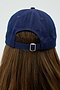 A person is seen from the back wearing a Tennis Cap - Indigo by SPLITS59, with long brown hair flowing beneath it.