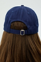 A person is seen from the back wearing a Tennis Cap - Indigo by SPLITS59, with long brown hair flowing beneath it.