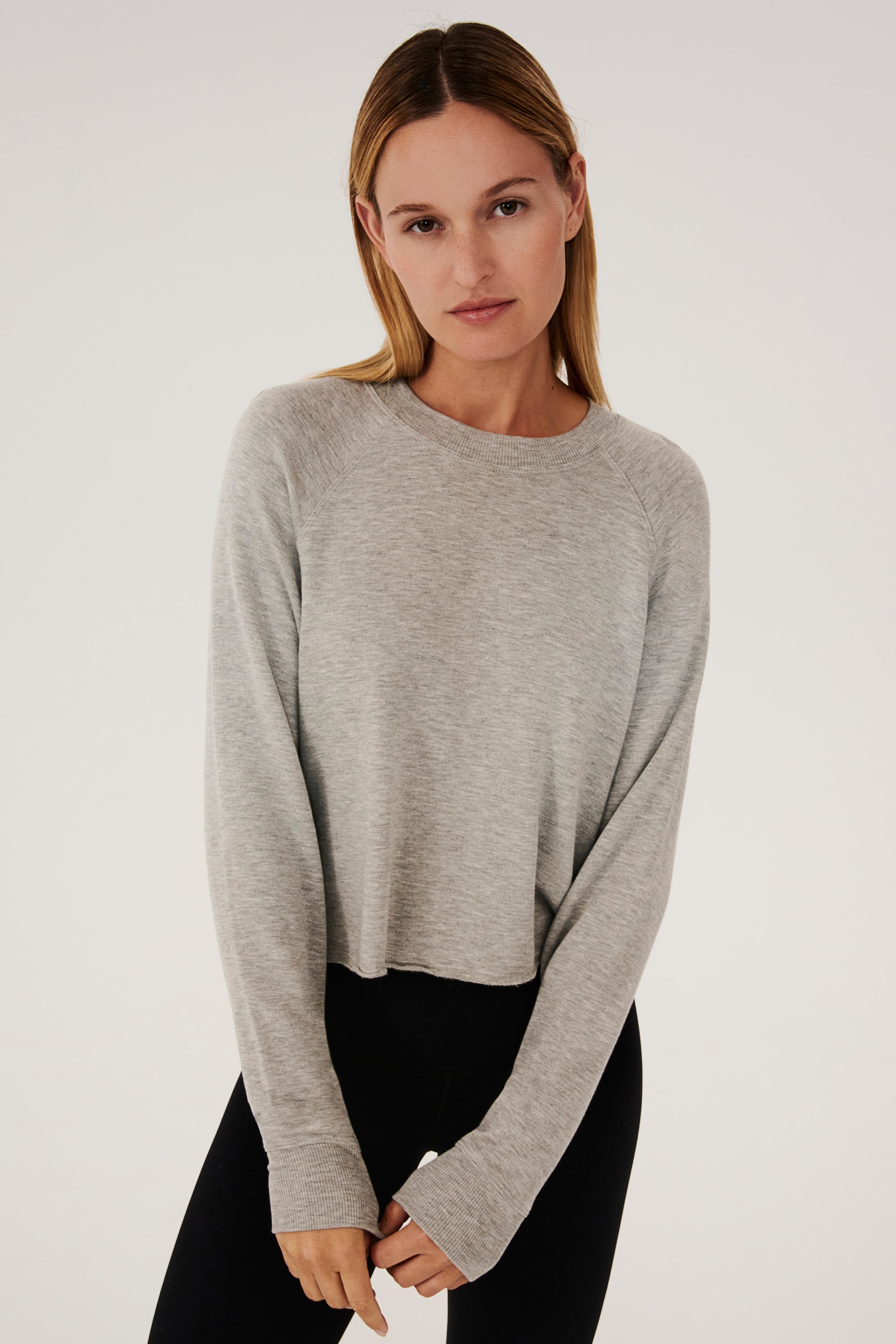 Front view of woman with dark blonde hair, wearing grey cropped sweatshirt with black leggings