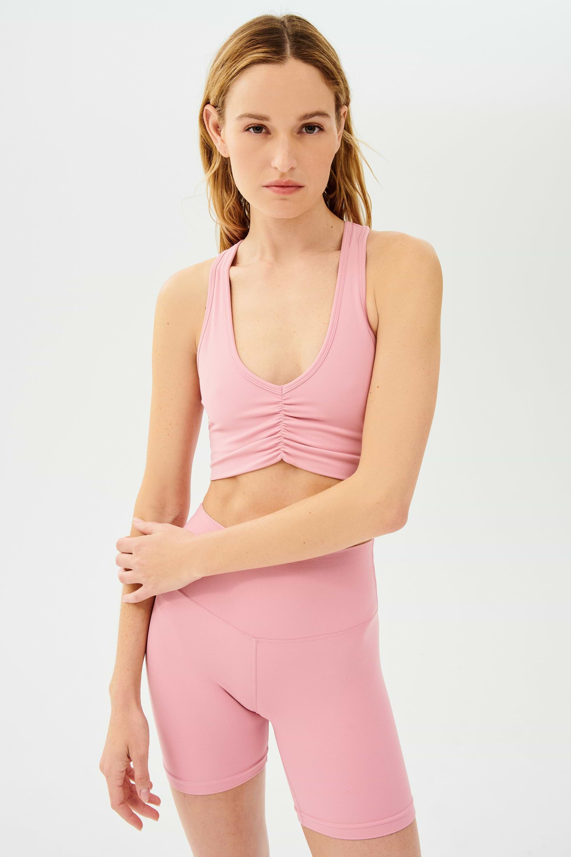 Front view of girl wearing scrunched sports bra in pink with pink bike shorts