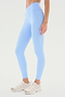 A person is shown from the waist down wearing the Mia Rigor 7/8 - Skylight high-waisted leggings by SPLITS59, made of superior performance fabric, paired with white athletic shoes, perfect for workout activities against a plain background.