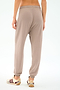 A person stands against a plain white background wearing SPLITS59’s Andie Oversized Fleece Sweatpant in Latte and white sneakers with maroon accents, an ideal look for cool-weather workouts.