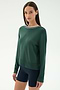A woman with straight brown hair wears the SPLITS59 Sonja Fleece Sweatshirt W/ Stripe in Military and navy spandex bicycle shorts, standing against a plain light background.