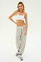A person with long hair wearing a white sports bra, the Andie Oversized Fleece Sweatpant in Heather Grey by SPLITS59, and sneakers stands against a plain white background.
