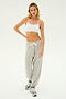 A person with long hair wearing a white sports bra, the Andie Oversized Fleece Sweatpant in Heather Grey by SPLITS59, and sneakers stands against a plain white background.