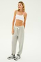 A person wearing a white crop top, the SPLITS59 Andie Oversized Fleece Sweatpant in Heather Grey, and grey sneakers stands against a plain white background, ready for cool weather workouts.