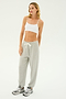 A person wearing a white crop top, the SPLITS59 Andie Oversized Fleece Sweatpant in Heather Grey, and grey sneakers stands against a plain white background, ready for cool weather workouts.