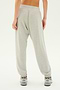 A person wearing the SPLITS59 Andie Oversized Fleece Sweatpant in Heather Grey and sneakers is shown from the back against a plain white background.