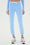 A person wearing the Sonja Fleece Sweatpant - Skylight by SPLITS59, featuring slouchy-soft, light blue fabric with white drawstrings, paired with gray sneakers—perfect for cool weather workouts.