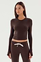 A person with long hair wears the SPLITS59 Louise Rib Long Sleeve Crop in Dark Chocolate and matching brown drawstring pants against a plain background.