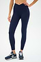 A person wearing SPLITS59's Mia Rigor 7/8 leggings in Indigo and dark blue sneakers stands against a plain background.