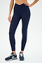A person wearing SPLITS59's Mia Rigor 7/8 leggings in Indigo and dark blue sneakers stands against a plain background.