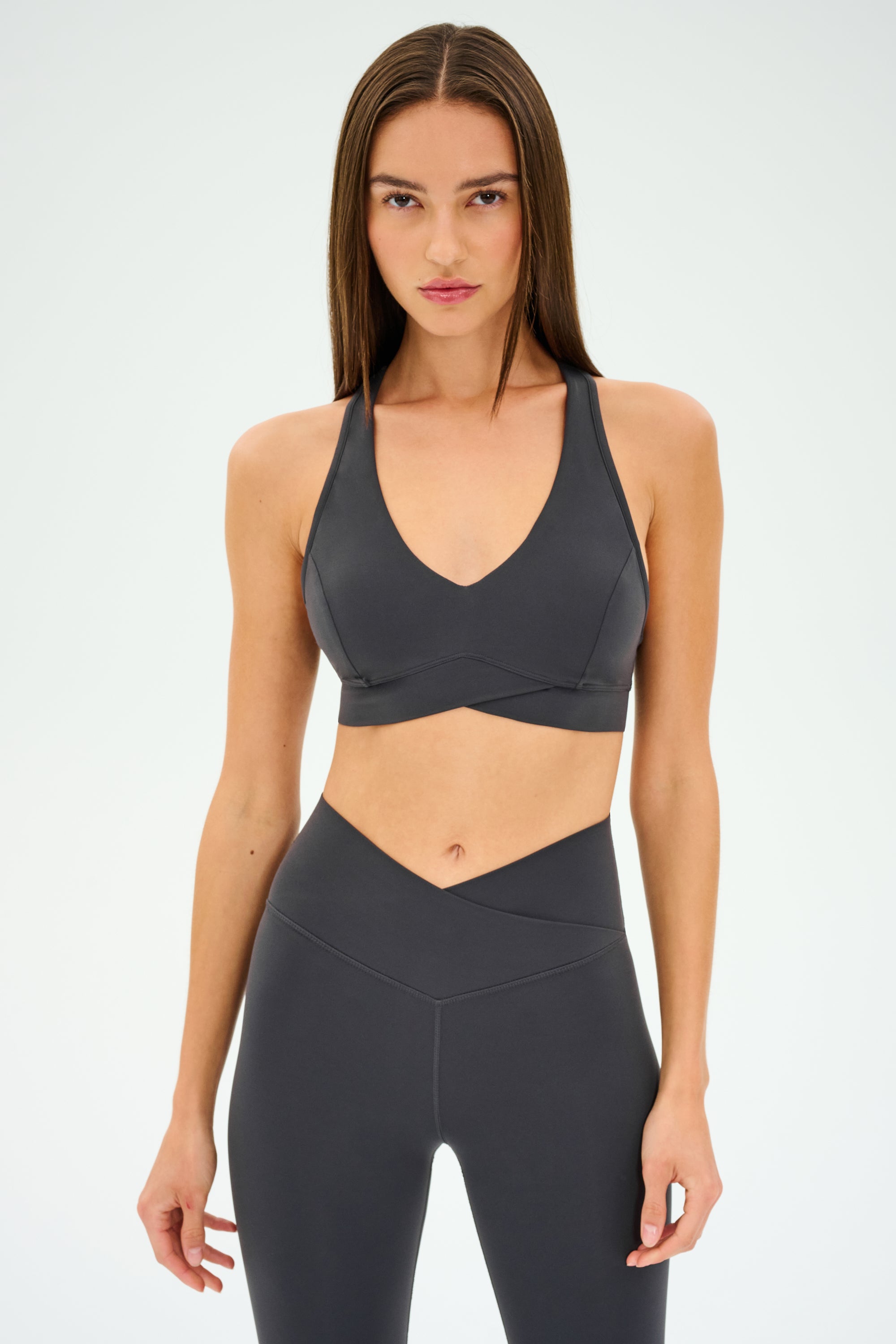 A woman wears the SPLITS59 MIA RIGOR BRA and matching high-waisted leggings, crafted from soft nylon spandex, standing against a plain light background.