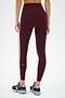 A person wears SPLITS59 Clare High Waist Rigor 7/8 leggings in Dark Cherry/Creme, accented with cream side stripes, paired with gray New Balance sneakers, standing against a plain white background.