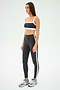 Someone wearing a black and white sports outfit featuring SPLITS59's Clare High Waist Rigor 7/8 leggings in Graphite/White and silver sneakers, ideal for gym workouts, stands confidently on a white background.