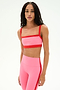 A person stands against a plain white background wearing the SPLITS59 Monah Rigor Bra in Strawberry/Lotus Red with matching high-waisted leggings.