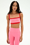 A woman wearing a SPLITS59 Monah Rigor Bra in Strawberry/Lotus Red and matching high-waisted leggings stands against a plain white background.