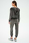 A woman in a Rhys Velour Zip Up Hoodie - Graphite by SPLITS59 stands with her back to the camera against a plain backdrop, showcasing comfort and versatility.