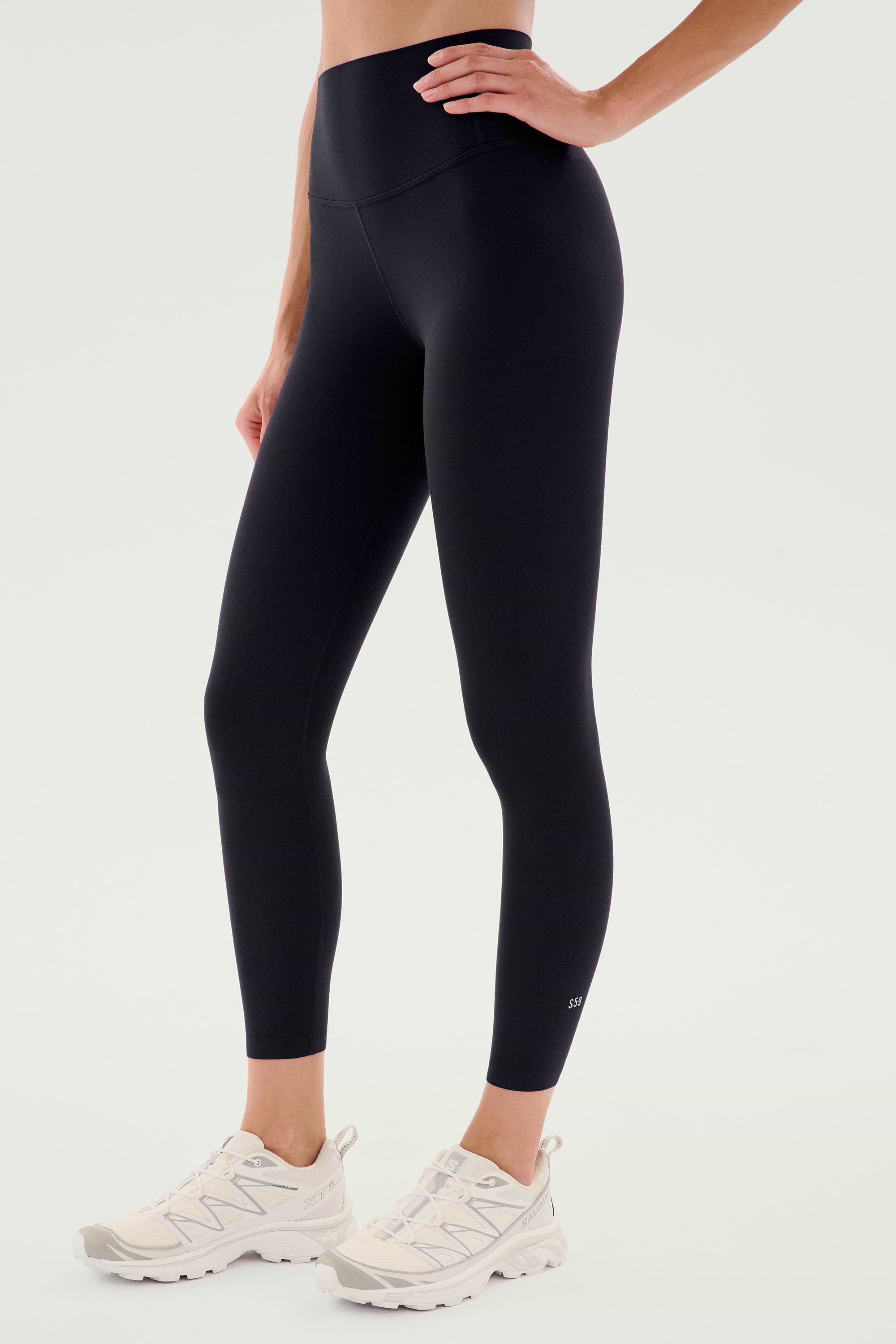 A person wears SPLITS59 Airweight High Waist Legging in black with white athletic sneakers, standing against a plain light background—ideal for hot yoga.