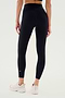 A person wearing SPLITS59 Airweight High Waist Legging in Black and white sneakers stands with their back to a plain background. Soft Airweight fabric makes them perfect for hot yoga or everyday comfort.