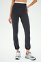 A person confidently stands with one hand on the hip, wearing SPLITS59's Icon Dual High Waist Airweight Legging in Graphite and gray sneakers against a plain background.