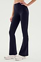 A person is wearing SPLITS59 Raquel High Waist Airweight Flare pants in black and white sneakers, photographed from the waist down. The person has one hand resting on their hip.