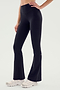 A person is wearing SPLITS59 Raquel High Waist Airweight Flare pants in black and white sneakers, photographed from the waist down. The person has one hand resting on their hip.