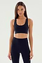 Person wearing a black Ella Airweight Bra by SPLITS59 and black high-waisted leggings, standing with arms relaxed by their sides.