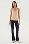 A person stands against a plain background wearing the Loren Seamless Waist Length Tank in Nude by SPLITS59, paired with black pants and white sneakers—perfect for gym workouts.