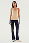 A person stands against a plain background wearing the Loren Seamless Waist Length Tank in Nude by SPLITS59, paired with black pants and white sneakers—perfect for gym workouts.